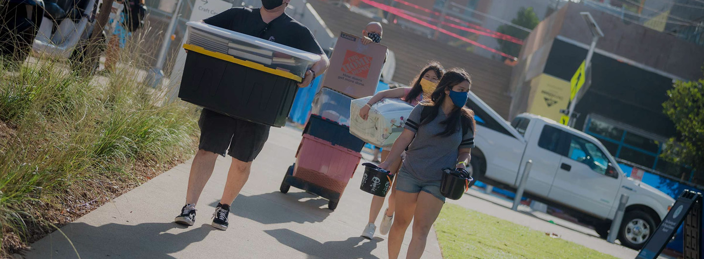 parents and students carrying boxes and move in items